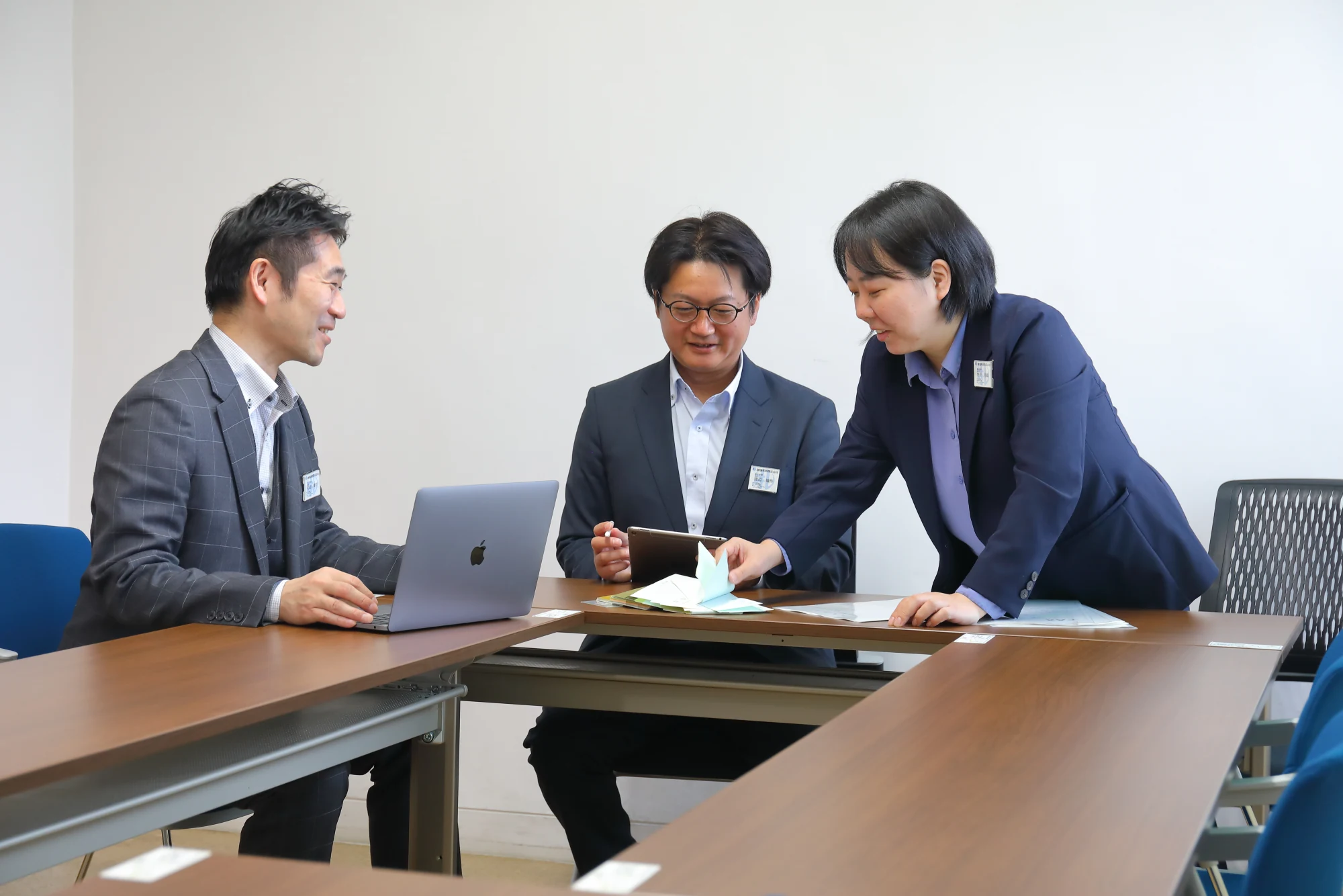 パソコンや資料を囲んで打ち合わせをする三人の社員